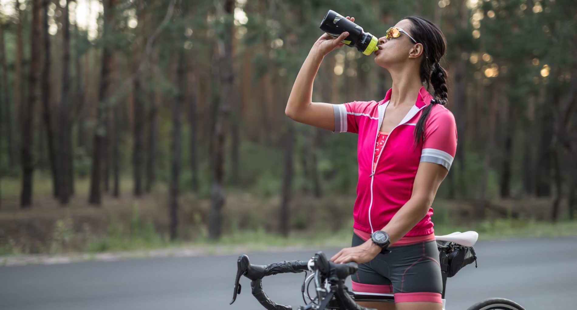 Woman on a sports bicycle drinking a sports drink