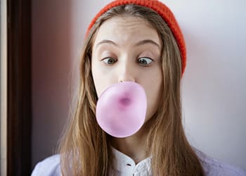 Teenager popping pink chewing gum