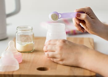 Hands mixing baby formula into a bottle