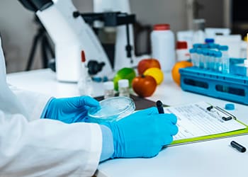 Scientist writing down quality test results while holding a petridish