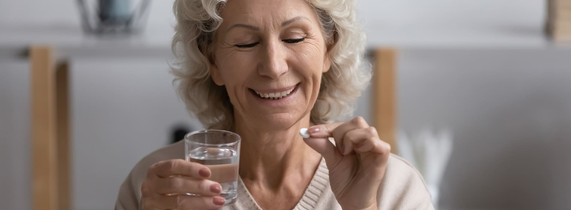 eldery woman sitting in bed and taking dietary supplement