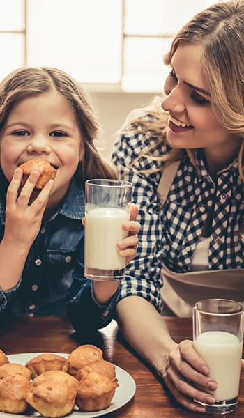 mother and daughter eating cookies and drinking milk