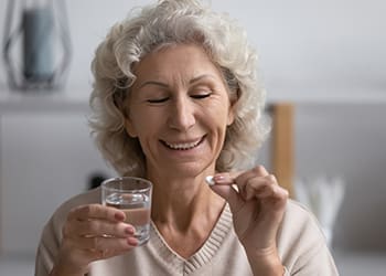 eldery woman sitting in bed and taking dietary supplement