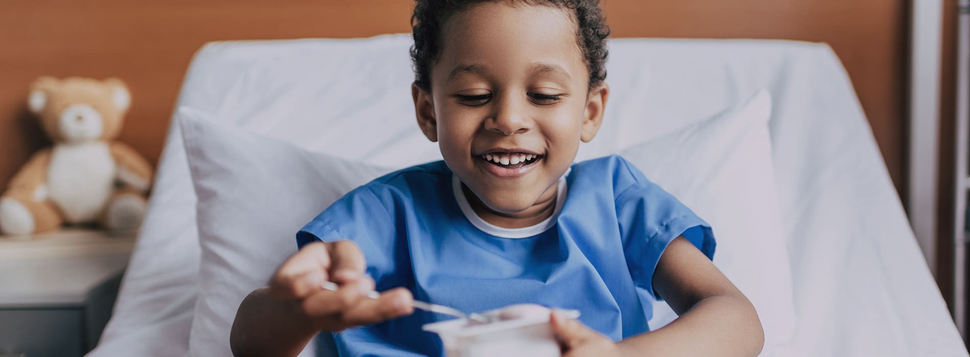 Boy in a hospitalbed eating yogurt